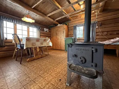 a room with a stove and a table in a cabin at Family cabin by the lake at Haugen, Femundsmarka in Elga