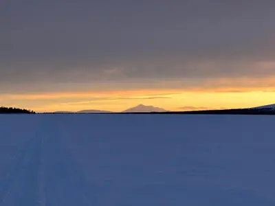 a large snow covered field with a sunset in the background at Simple family cabin at Haugen, Femundsmarka in Elga