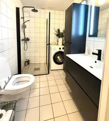a bathroom with a toilet and a sink and a shower at Delicate Central Apartment Trondheim in Trondheim