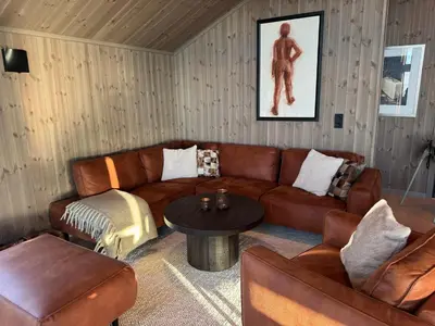 a living room with brown leather furniture and a table at New modern cabin in Beitostølen in Beitostøl