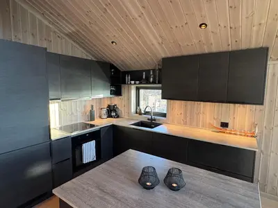 a kitchen with black cabinets and a wooden ceiling at New modern cabin in Beitostølen in Beitostøl