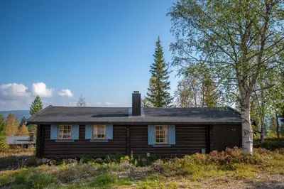 a wooden house with a chimney on top of a hill at Trysilfjellet Sør 204 in Trysil