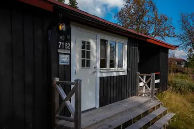 a small black shack with a white door at Trysilfjellet Nord 1071B in Trysil