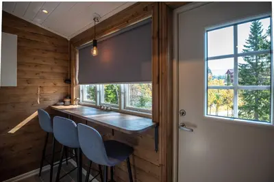 a kitchen with a bar with blue chairs and a window at Trysilfjellet Nord 1071B in Trysil