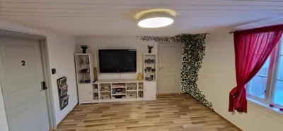 a living room with a television and red curtains at Storgata 36B in Lillehammer