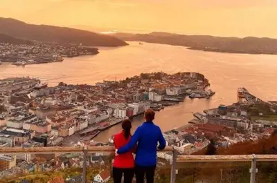 a man and a woman standing on a ledge overlooking a city at DINBNB Apartments Private terrace l 700 m to Bryggen l Modern in Bergen