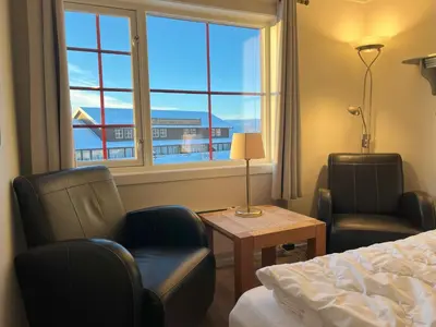 a hotel room with a bed and two chairs and a window at Bitihorn fjelltind in Beitostøl