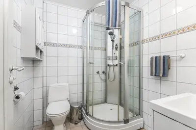 a white bathroom with a shower and a toilet at Beautiful and central apartment for rent during Ski WC 2025 in Trondheim