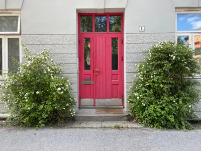 a red door on a house with two bushes at Beautiful and central apartment for rent during Ski WC 2025 in Trondheim