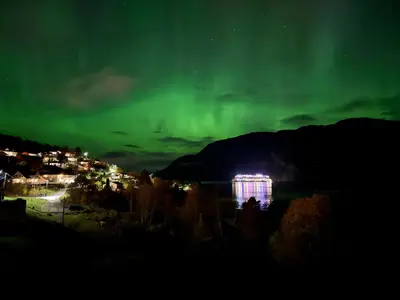 an aurora over a city at night with a building at FjordView in Stranda
