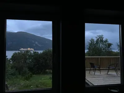two chairs on a deck with a view of a ship in the water at FjordView in Stranda