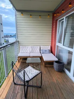 a porch with a couch and a table and a chair at Romslig og pen leilighet - sentral beliggenhet in Charlottenlund