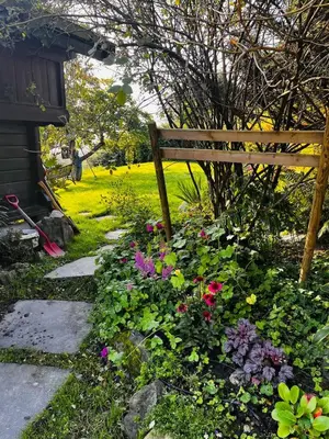 a garden with a wooden bench and some flowers at Fairy tale house during Ski world cup in Melhus