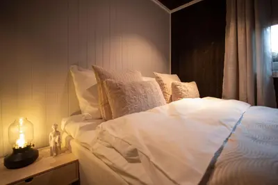 a bed with white sheets and pillows next to a window at Studio Plassen in Sogndal