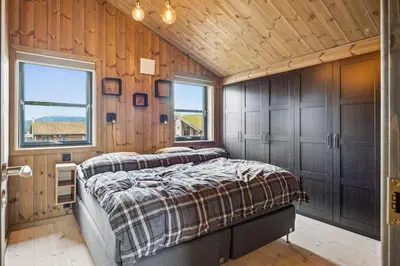 two beds in a room with wooden walls and windows at Very central and fresh apartment 4 bedr, 10p 2 floors, sauna, ski in and out in Trysil