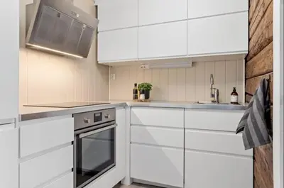 a white kitchen with white cabinets and a sink at Koselig leilighet på Møllenberg in Trondheim
