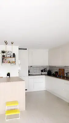 a kitchen with white cabinets and a yellow stool at Townhouse in quiet and central area with free parking in Trondheim
