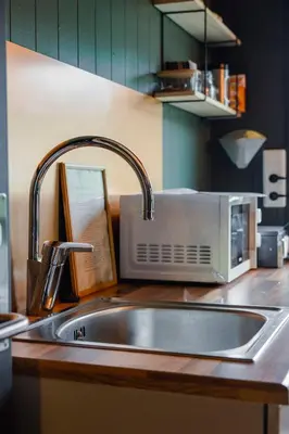 a kitchen counter with a sink and a microwave at Bergmannshuset in Løkken