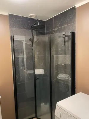 a shower with a glass door in a bathroom at 2 etasjers leilighet in Trondheim