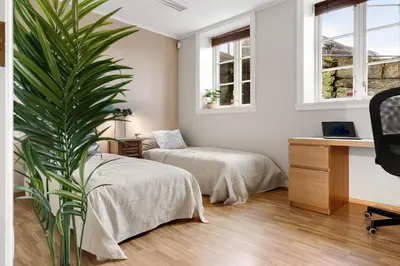 a bedroom with two beds and a desk and a plant at Stilfull sentrumsnær leilighet in Bergen