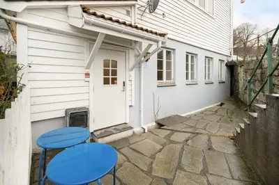 two blue stools in front of a white house at Stilfull sentrumsnær leilighet in Bergen