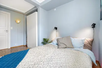 a bedroom with a large bed with a blue blanket at Stilfull sentrumsnær leilighet in Bergen