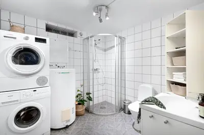 a bathroom with a washing machine and a shower at Stilfull sentrumsnær leilighet in Bergen