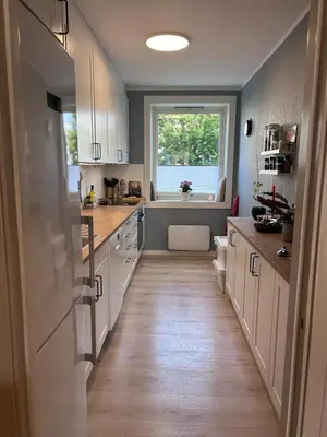 a large kitchen with white cabinets and a window at 2 bed apartment in Trondheim