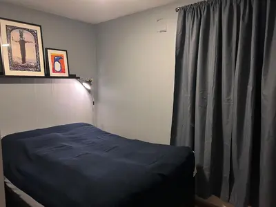 a bedroom with a blue bed and a curtain at 2 bed apartment in Trondheim