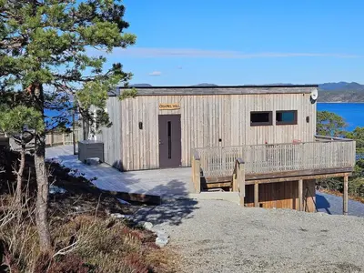 a wooden building with a door on a beach at Large modern cabin with a spectacular view! in Grønningen