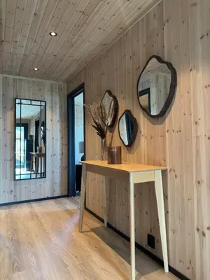 a table with two mirrors on a wooden wall at Large modern cabin with a spectacular view! in Grønningen