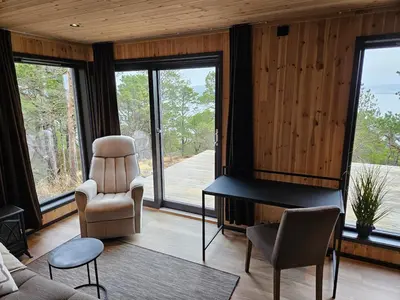 a living room with a couch and a chair and windows at Large modern cabin with a spectacular view! in Grønningen