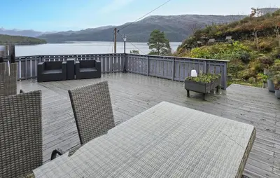 a patio with a table and chairs and a view of the water at Beach Front Home In Omastrand in Gjuvsland