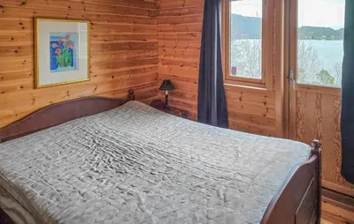 a bedroom with a bed in a room with a window at Beach Front Home In Omastrand in Gjuvsland