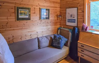 a couch in a room with a wooden wall at Beach Front Home In Omastrand in Gjuvsland