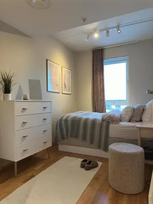 a bedroom with a bed with a dresser and a window at Spacious apartment with a great view and parking in Trondheim