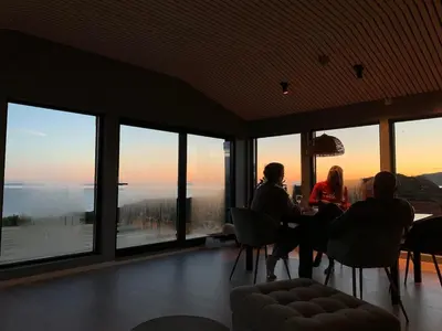a group of people sitting at a table in a room with windows at Great cottage with unique views and high standard in Tørhogg