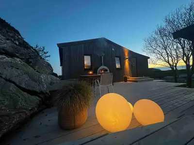 a small black house with a deck with a table at Great cottage with unique views and high standard in Tørhogg