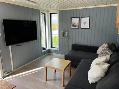 a living room with a couch and a tv at Great cottage with unique views and high standard in Tørhogg