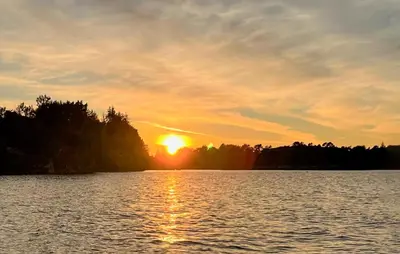 a sunset on a lake with the sun setting at Stunning Home In Torangsvåg in Skår