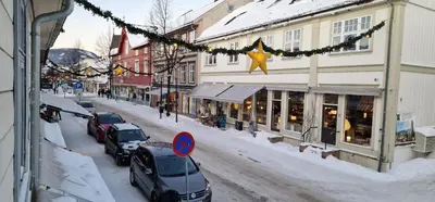 a snowy street with cars parked in front of a building at Storgata 36 in Lillehammer