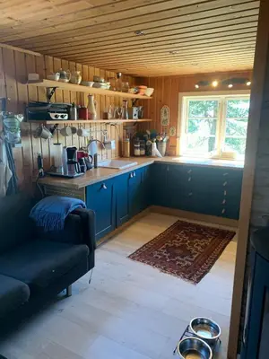 a kitchen with blue cabinets and a couch and a window at Cabin at Kvamskogen with a great view in Kvam