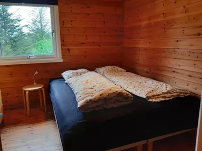 a bed in a wooden room with a window at Cabin 