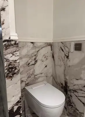 a white toilet in a bathroom with marble walls at Apartment in city centre with view of the canal in Trondheim