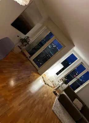 a living room with two large windows and a couch at Apartment in city centre with view of the canal in Trondheim