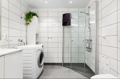 a white bathroom with a washing machine and a shower at Fin leilighet for VM in Trondheim