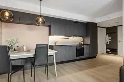 a kitchen with a white table and black cabinets at Fin leilighet for VM in Trondheim