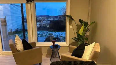 a living room with two chairs and a large window at Modern apartment with stunning view over city in Trondheim