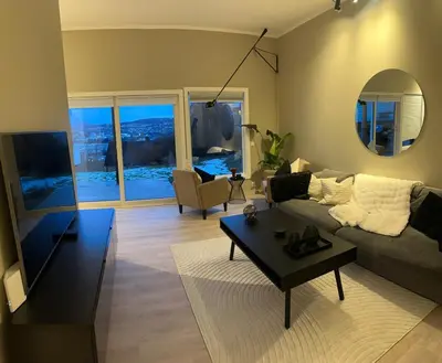 a living room with a couch and a table at Modern apartment with stunning view over city in Trondheim