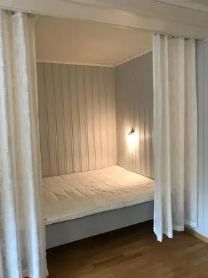 a bed in a room with curtains and a light at Bright and nice apartment in Trondheim